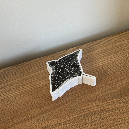 Decorative vinyl spotted eagle ray sticker on a wooden surface.